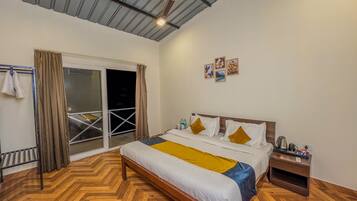 Una camera da letto con un letto, un comodino, una ventola a soffitto e una porta scorrevole in vetro che dà su un balcone.