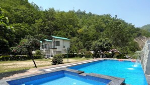 Una piscina rettangolare con bordo piastrellato, circondata da un solarium in legno.