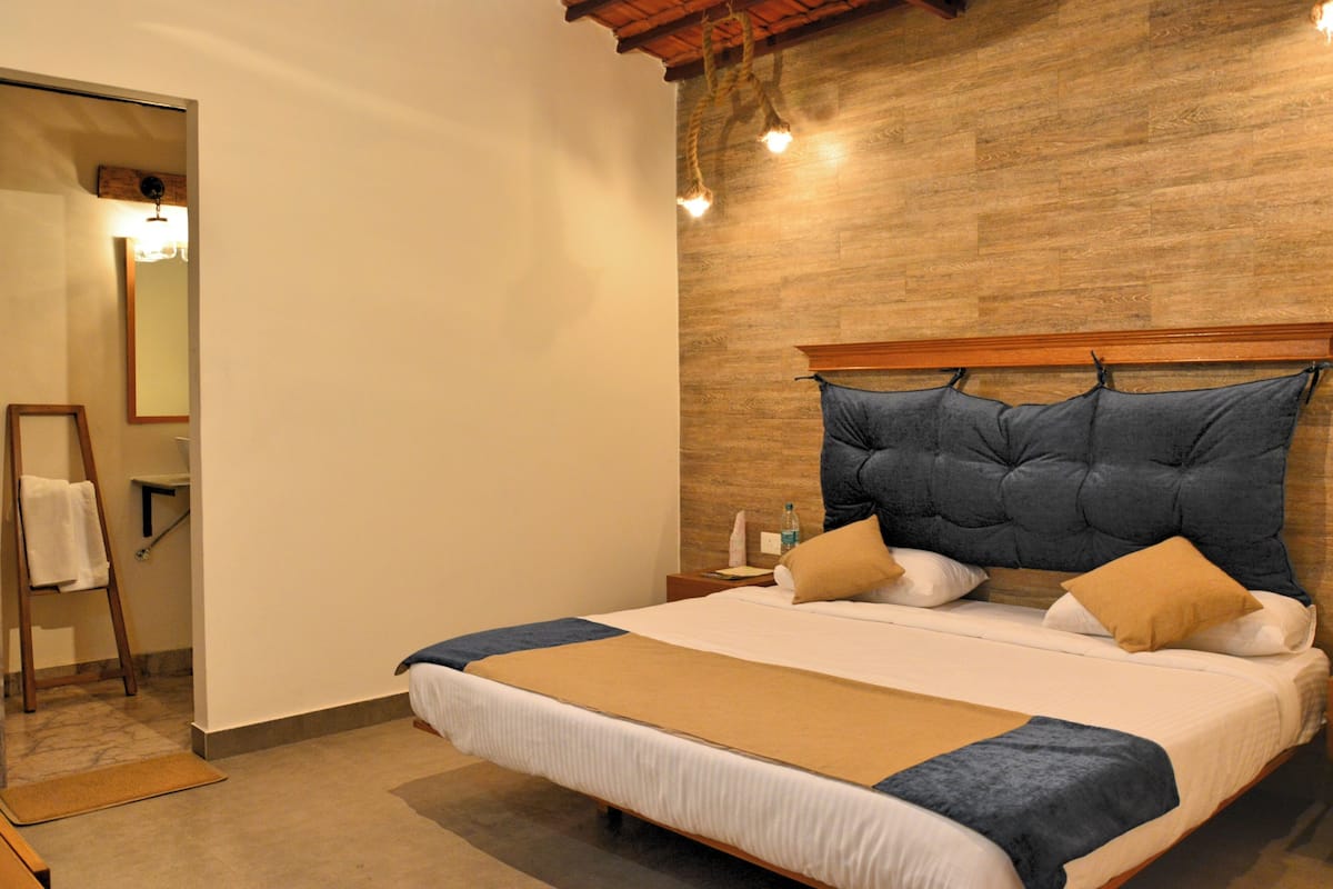 A bedroom with a large bed, wooden headboard, and a wooden floor.