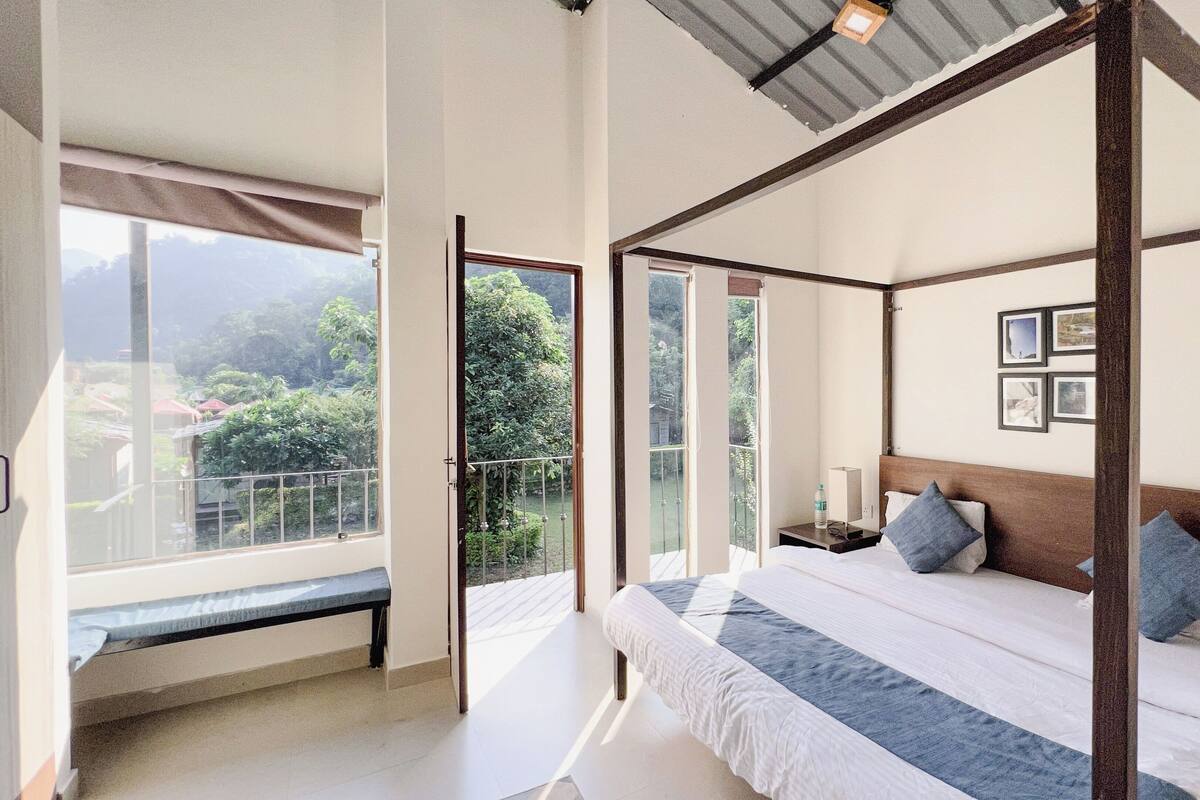 A four-poster bed with a view of greenery outside.