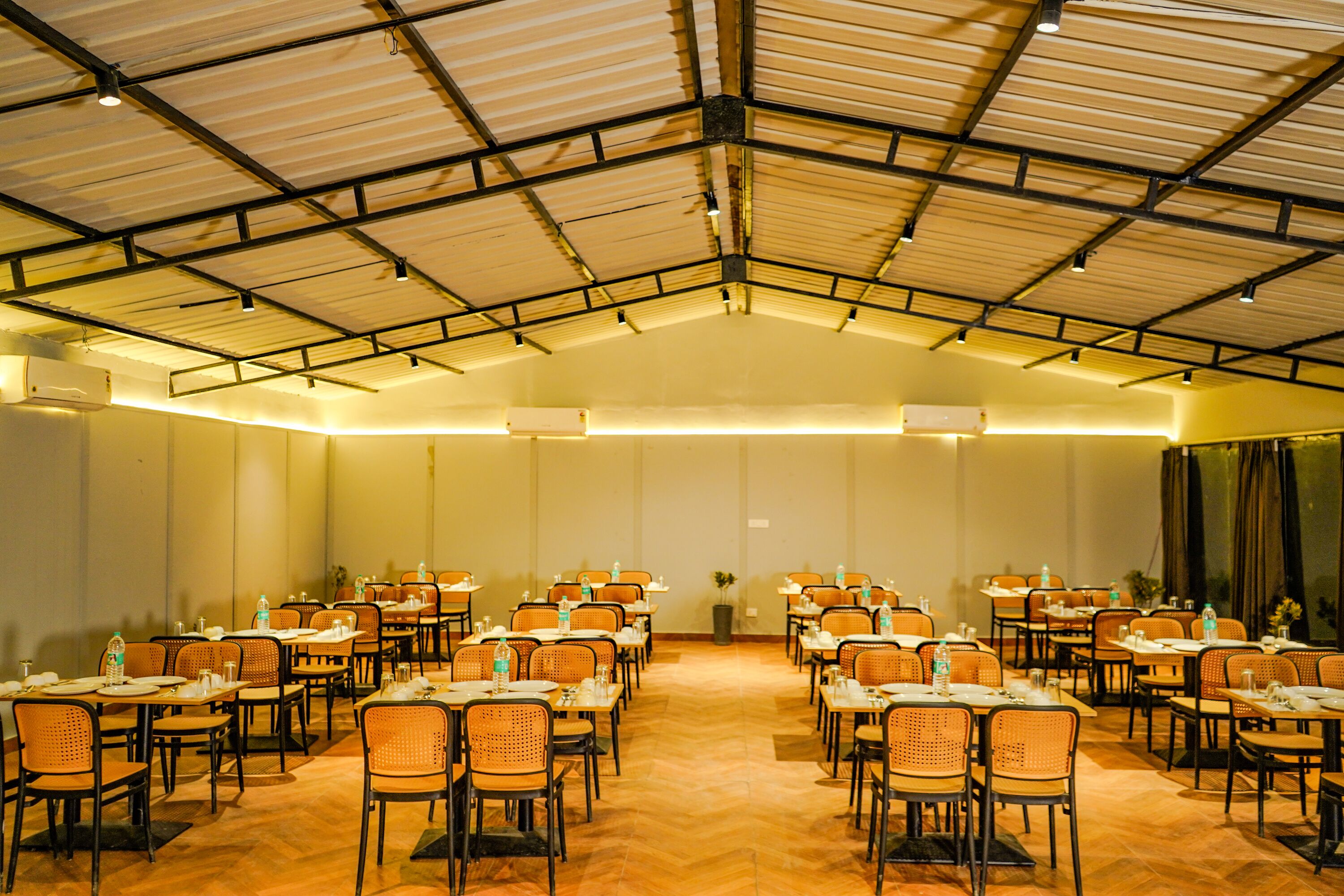 A large hall with rows of tables and chairs, arranged for a meeting or event.