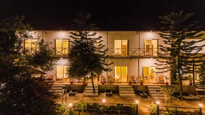 A two-story building with a balcony, outdoor seating area, and potted plants.