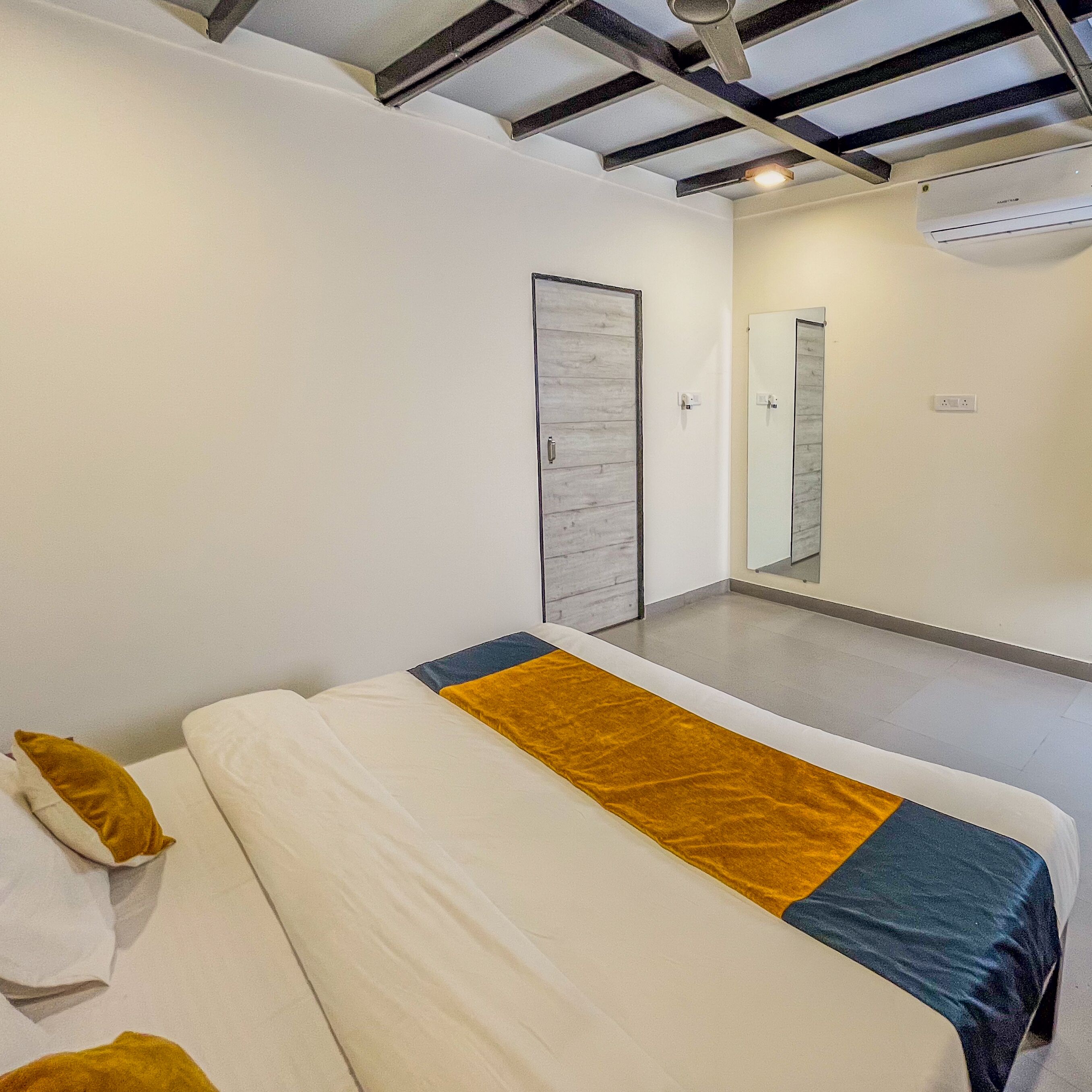 Un dormitorio moderno con cama, armario, espejo y equipo de aire acondicionado.