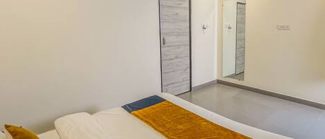 Un dormitorio moderno con cama, armario, espejo y equipo de aire acondicionado.