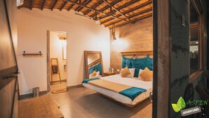 Una camera da letto con soffitto in legno, un letto con biancheria azzurra e beige, una scala di legno e uno specchio appeso al muro.