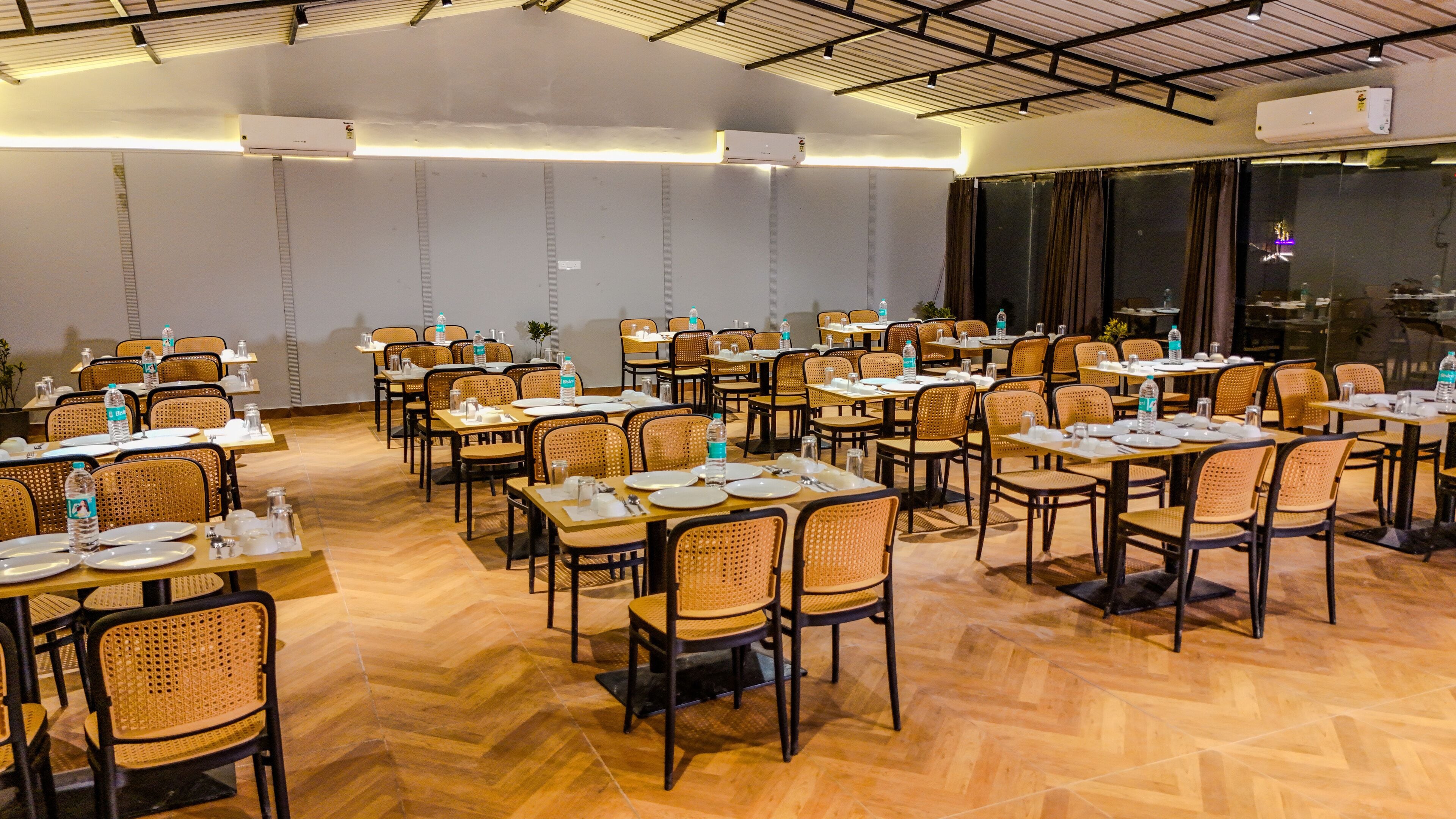 A conference room with multiple tables and chairs, equipped with water bottles and table settings.