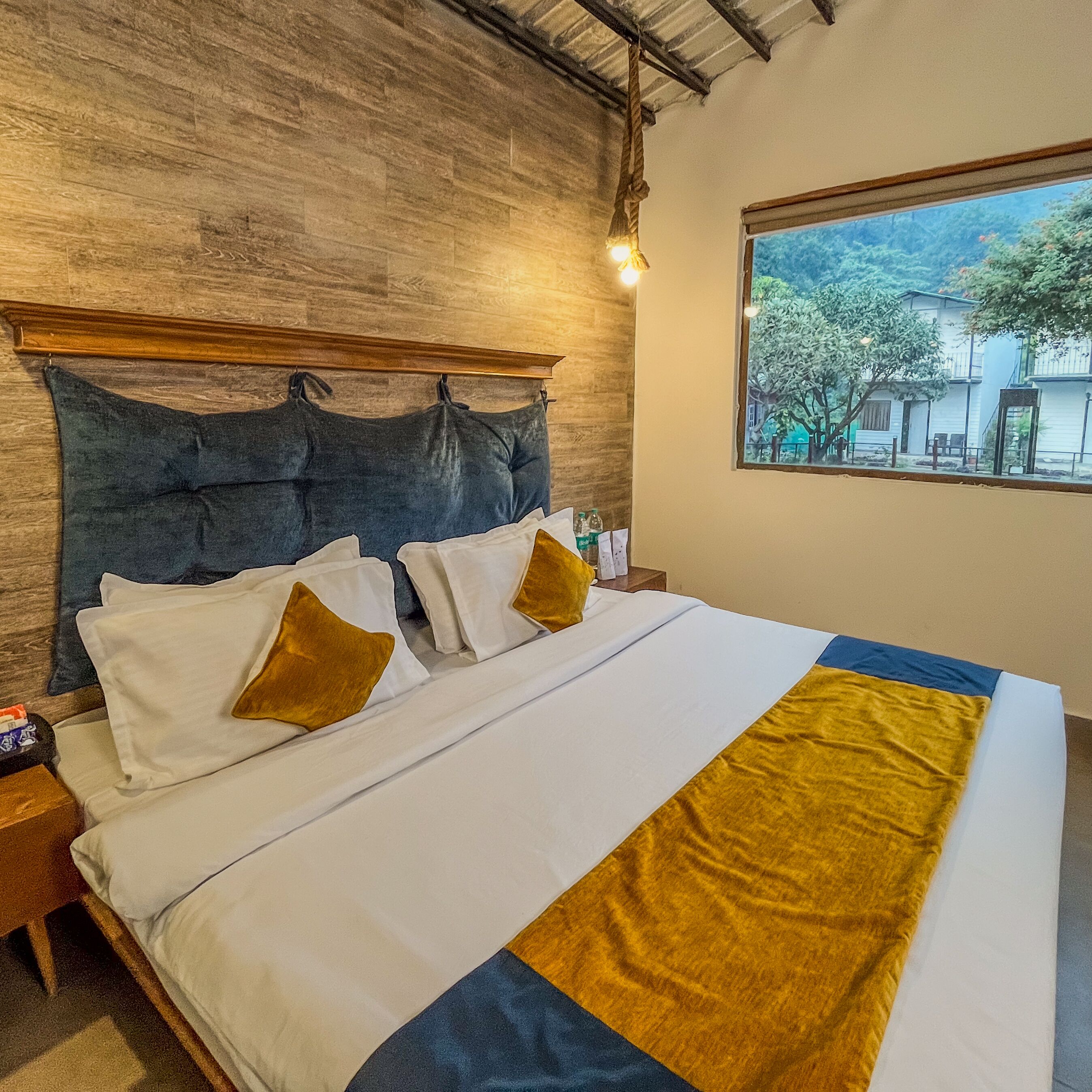 A bed with white and gold pillows, a blue and gold throw blanket, and a wooden headboard.