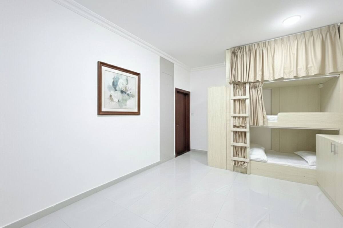Un dormitorio con una cama litera, un armario y un cuadro en la pared.