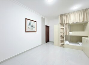 Een slaapkamer met een stapelbed, een kledingkast en een ingelijste foto aan de muur.