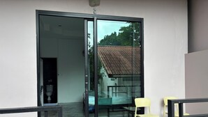 Een kamer met een schuifdeur naar een balkon, een klein tafeltje en een stoel.