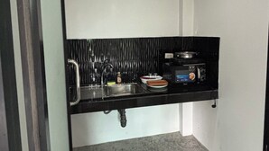 Een kleine keuken met een zwart aanrecht, een spoelbak, een raam en een fornuis.