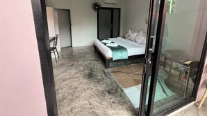 Quarto com cama, escrivaninha e cadeira. Há uma porta de vidro deslizante que dá para uma varanda.