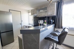 A modern kitchen with a built-in island, stainless steel appliances, and bar stools.