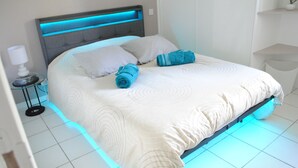 A bed with a headboard, pillows, and rolled towels. - Welcome to Le Cocon Châtillonais apartment in the center of Châtillon sur Chalaronne (Châtillon-sur-Chalaronne)