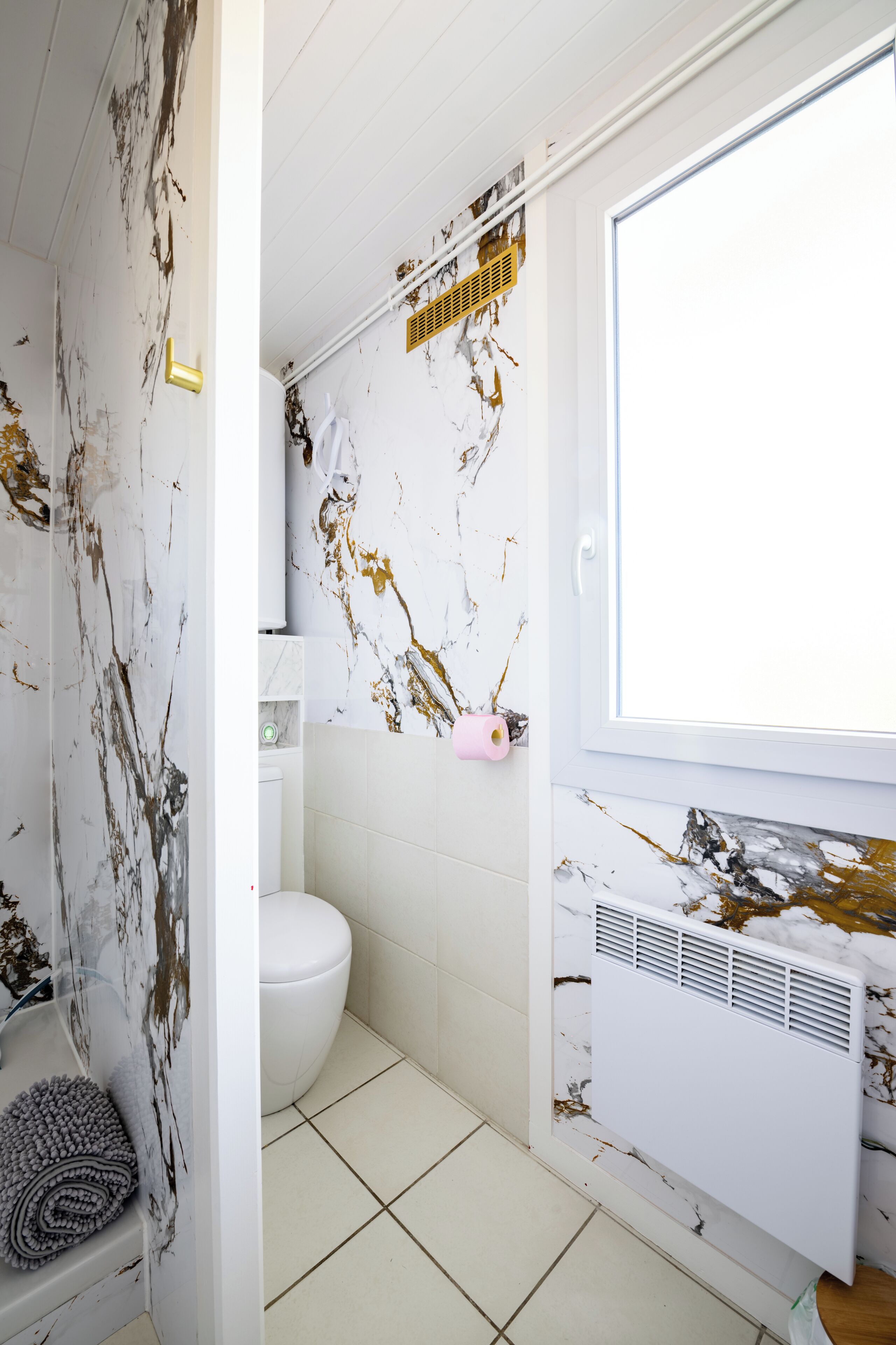 A bathroom with a white toilet, a bathtub, and a window.