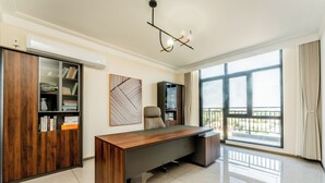 A modern office space with a wooden desk, a bookshelf, and a large window with a view. - Beijing Daxing Apartment  (Vientiane)