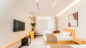 A modern hotel room with a bed, desk, and TV. - Beijing Daxing Apartment  (Vientiane)
