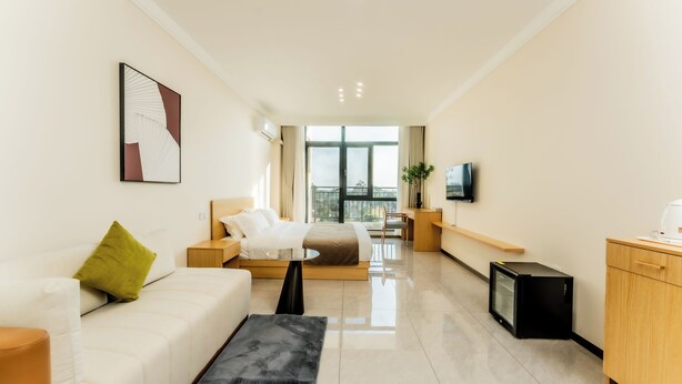 A modern hotel room with a sofa, a small table, a TV, and a desk. - Beijing Daxing Apartment  (Vientiane)