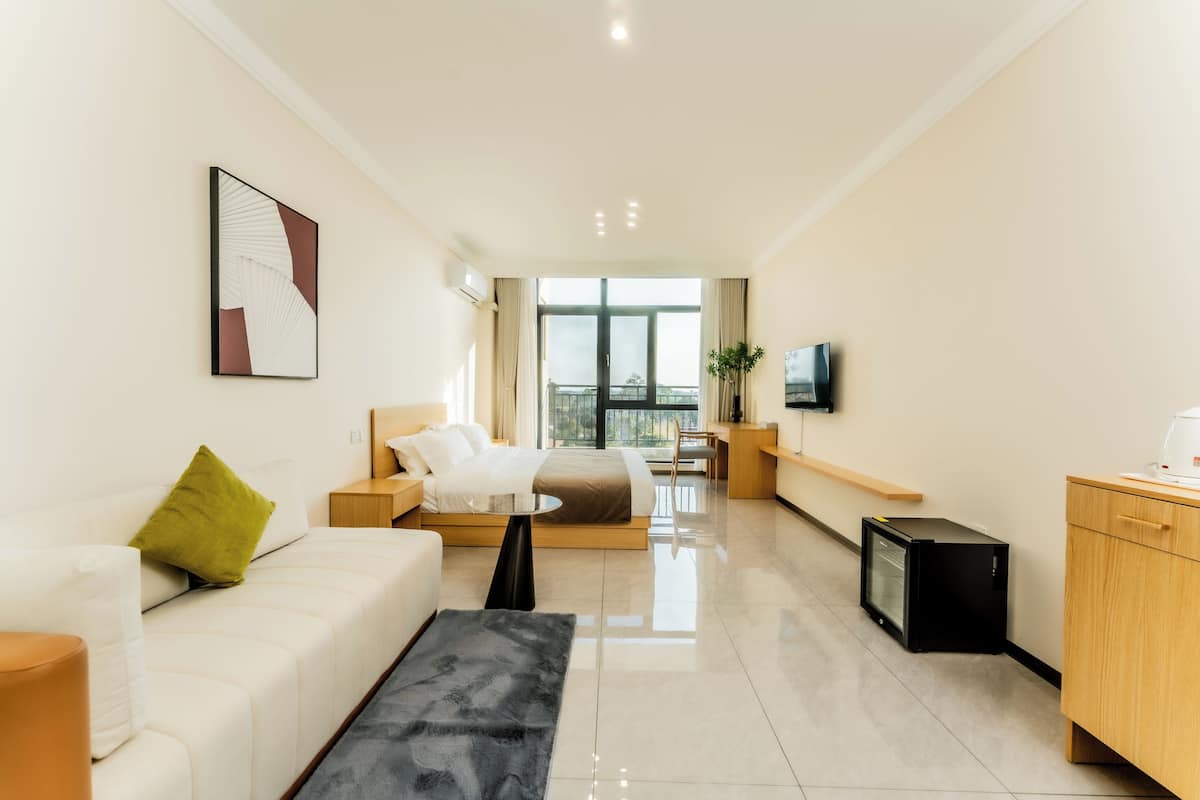 Una habitación de hotel moderna con sofá, una mesita, televisor y escritorio.