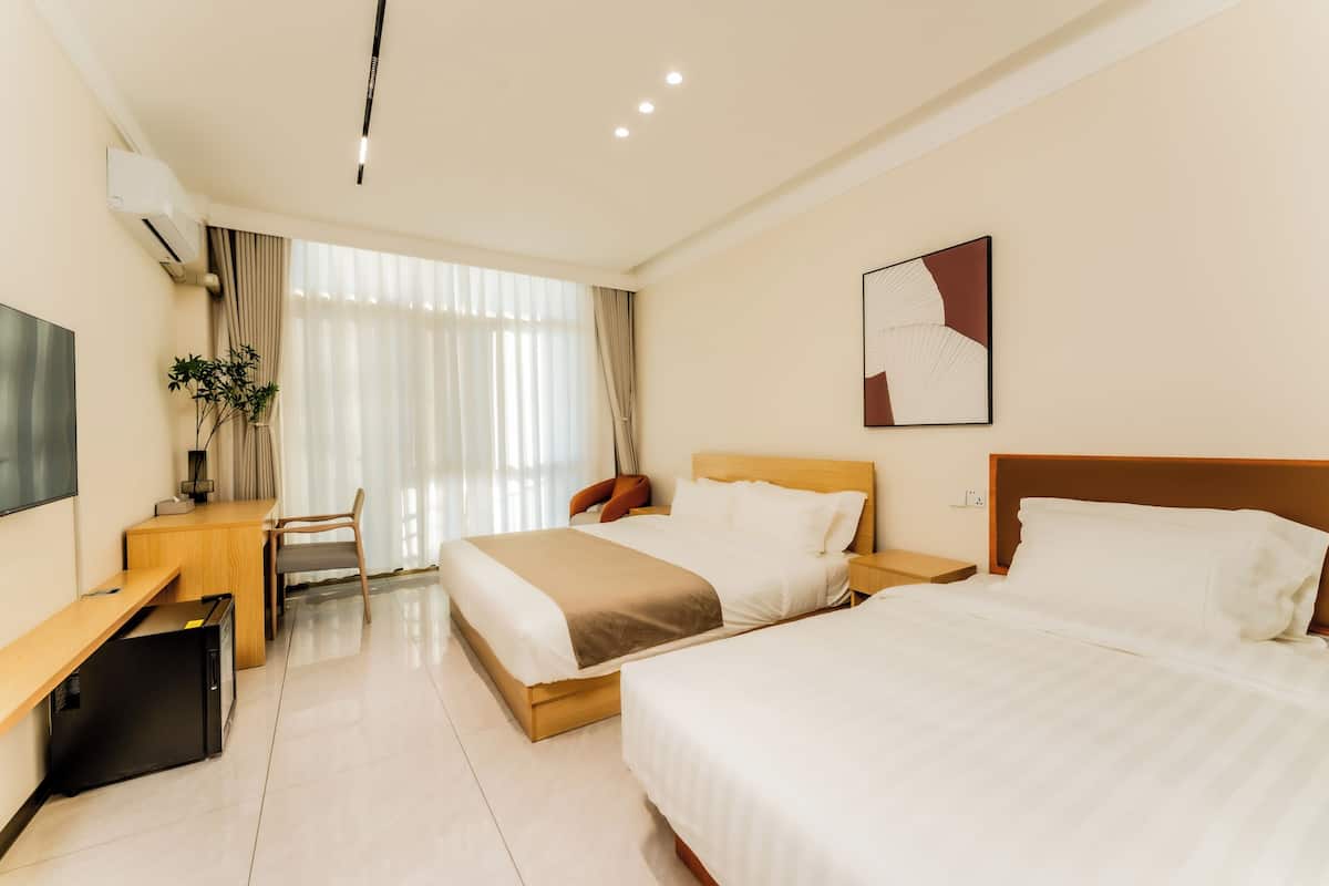 Habitación de hotel con dos camas, un escritorio, una silla, un televisor y una ventana con cortinas.