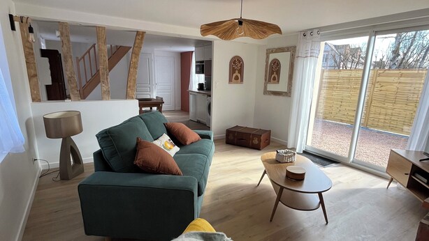 A spacious living room with a sofa, a yellow armchair, and a dining table. - House with spa and terrace - village with amenities on foot (Acquigny)