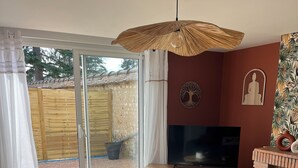 A living room with a sofa, a TV, a wooden coffee table, and a ceiling fan. - House with spa and terrace - village with amenities on foot (Acquigny)