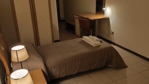 Habitación de hotel con dos camas, un escritorio, una silla y una lámpara.