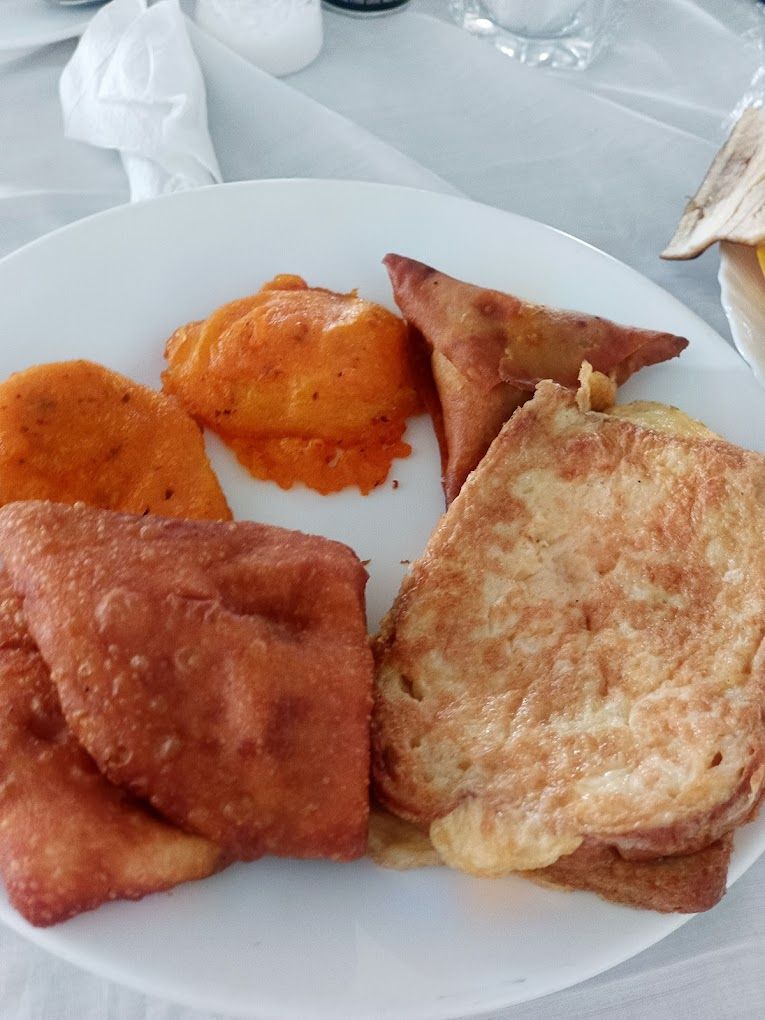Un plato con un sándwich a la plancha, una papa al horno y dos porciones de comida frita.