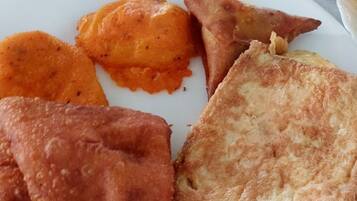 Un plato con un sándwich a la plancha, una papa al horno y dos porciones de comida frita.