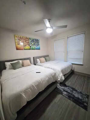 A bedroom with two beds, a ceiling fan, a painting, and a window with blinds. - Luxury Frisco with 2 queen beds sleeps 4 resort like Stay! (Frisco)