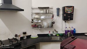 Eine Küche mit Gasherd, Geschirrgestell, Wasserspender und einem roten Stuhl.