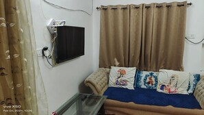 Ein Schlafzimmer mit einem Bett, einem an der Wand montierten Fernseher und einer Steckdose.