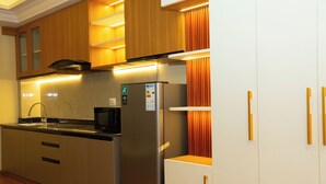 A modern kitchen with stainless steel appliances, wooden cabinets, and a built-in microwave. - Batuwa Homes (Kathmandu)