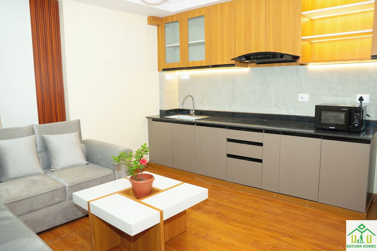 A compact kitchen with a grey sofa, a white coffee table, and a potted plant.