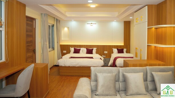 A hotel room with a large bed, a sofa, a desk, and a wardrobe. - Batuwa Homes (Kathmandu)
