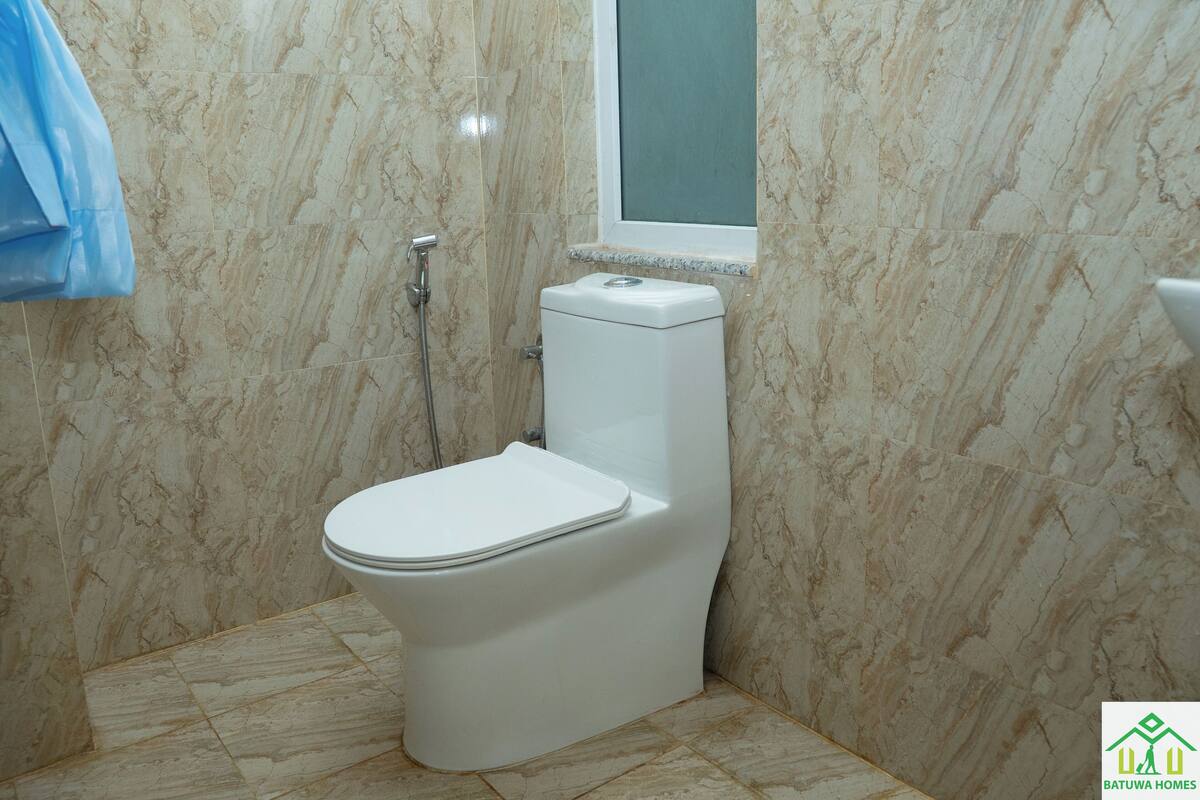 A bathroom with a toilet, a shower, and a window.