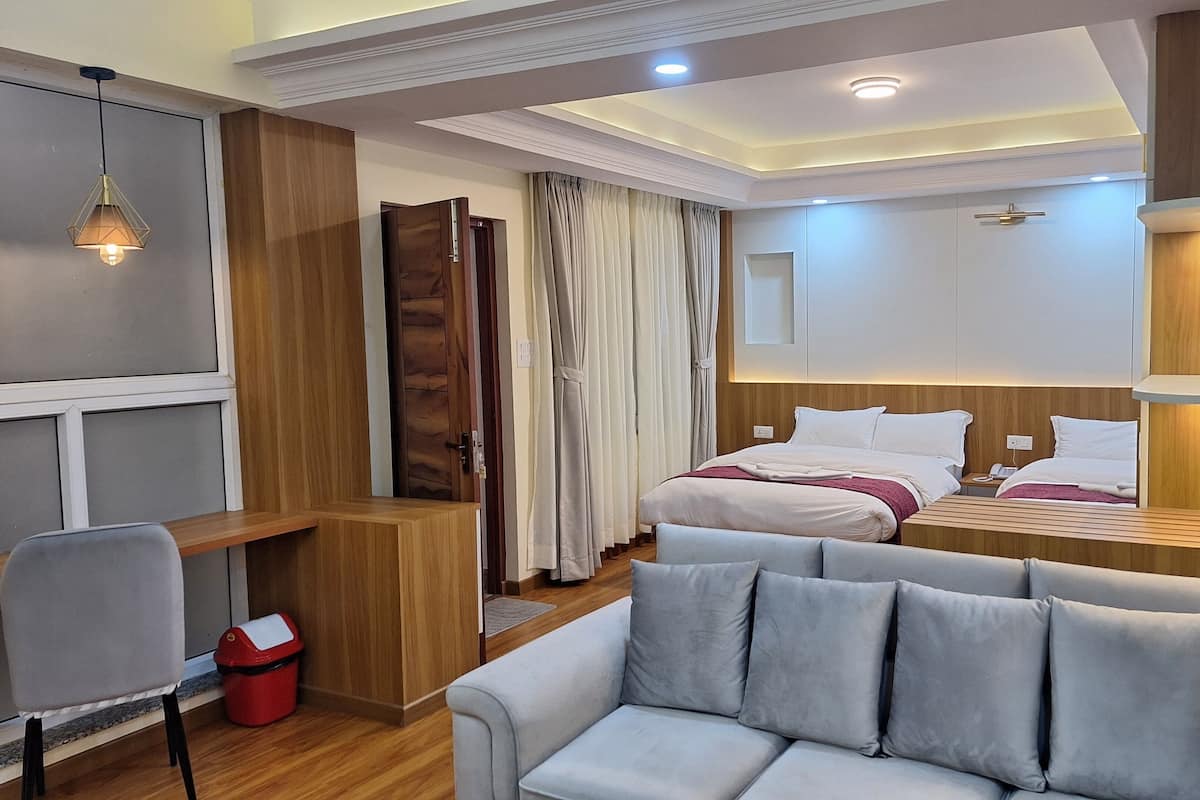 A hotel room with a bed, a sofa, a desk, and a chair.