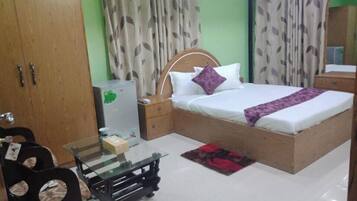 A bedroom with a bed, nightstand, wardrobe, and a glass table.