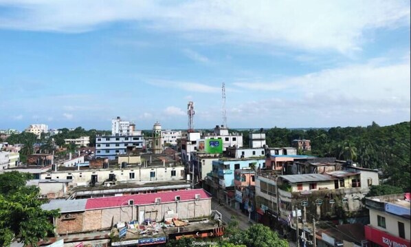 A densely built urban area with various buildings, including multi-story structures and smaller houses, under a clear sky. - Hotel Grand Safeer Jamalpur (Jamalpur)
