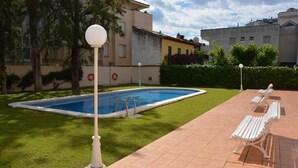 Piscina con borde de baldosas, rodeada de césped y árboles.