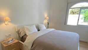 Un dormitorio moderno con cama, mesita de noche de madera, lámparas de noche y ventilador de techo.