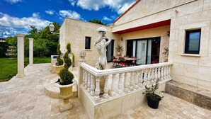 A building with a balcony, columns, and potted plants. - SECRET HOUSE- La Villa Rom'Antiqua - Ancient immersive experience (Néfiach)