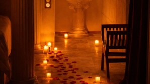 A statue in a corridor with candles and rose petals on the floor. - SECRET HOUSE- La Villa Rom'Antiqua - Ancient immersive experience (Néfiach)
