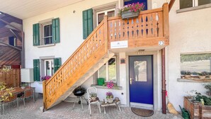 A multi-level building with a wooden staircase, a blue door, and outdoor seating with potted plants. - Boutique apartment in the Wynental valley in the triangle between Bern, Zurich and Lucerne. (Reinach)