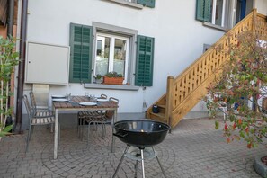 Un patio con mesa, sillas, una parrilla y una escalera.