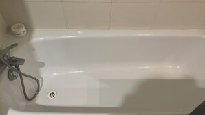 Amme, jossa on irrotettava suihkupää, pohjaventtiili ja pullo shampoota.