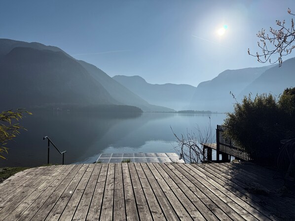 Un muelle de madera que se extiende hacia un lago tranquilo, con montañas al fondo.
