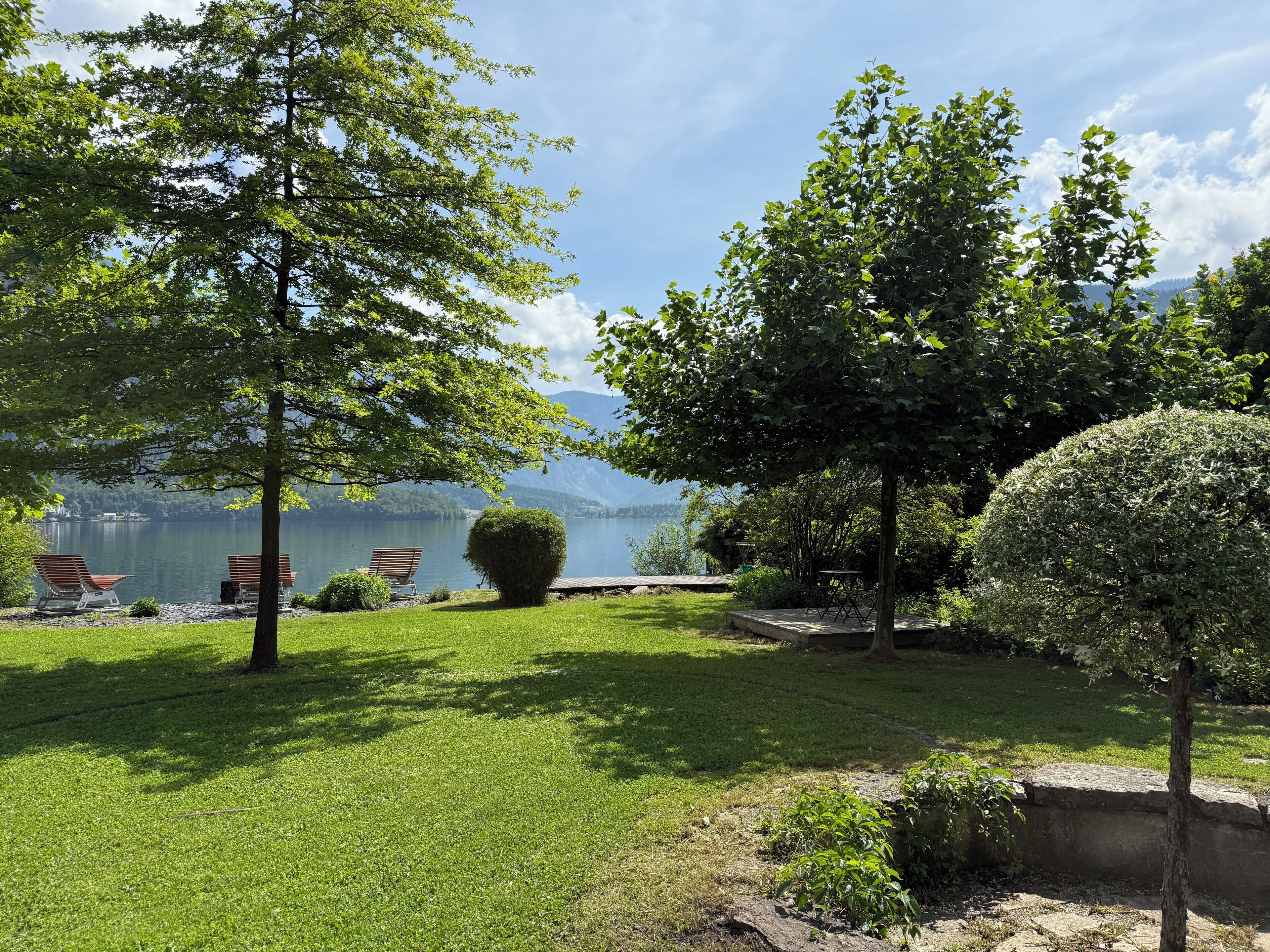 A serene outdoor area with a lake, trees, and a bench.
