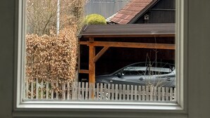 A mountain landscape through a window, a wooden building with a car parked outside, and a white picket fence.