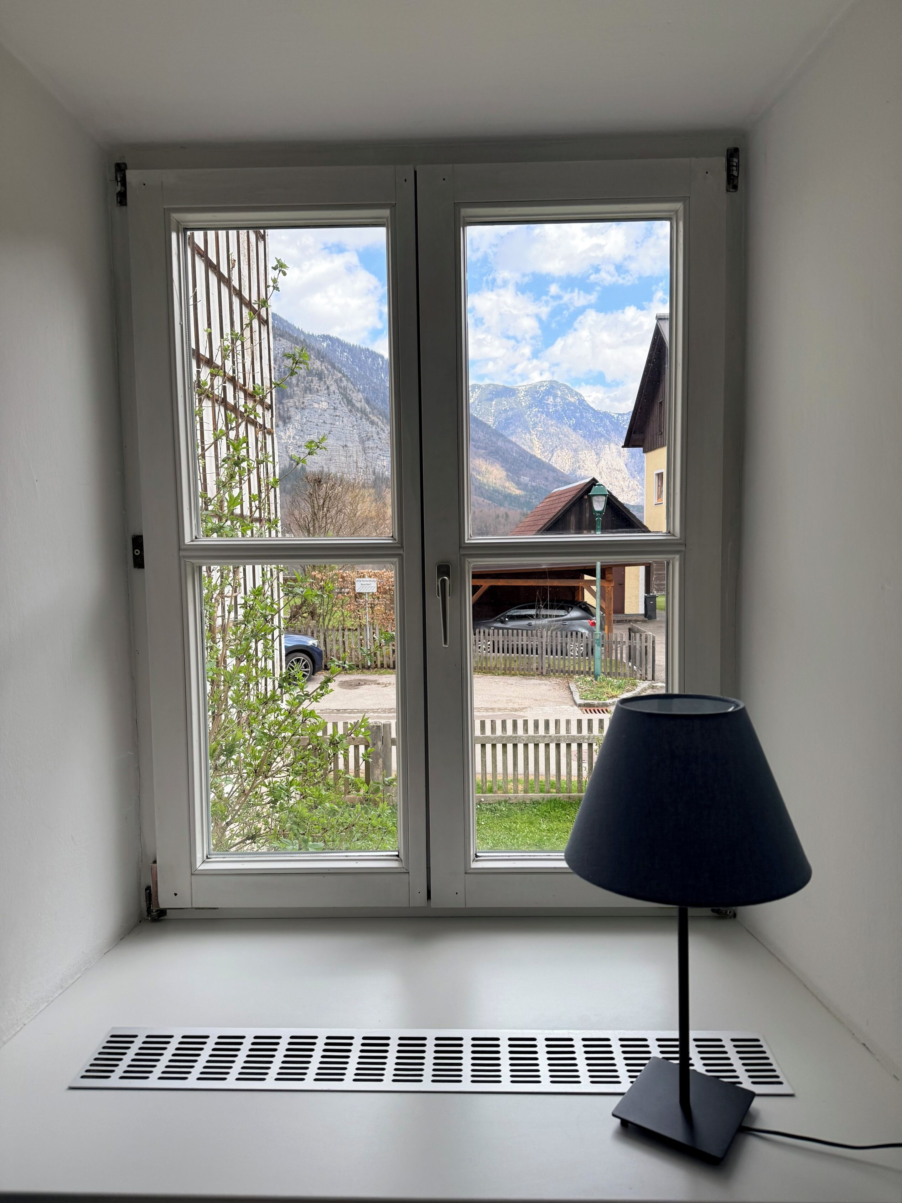 Ein Zimmer mit Fenster und Blick auf eine Berglandschaft, einem Heizkörper und einer Lampe.